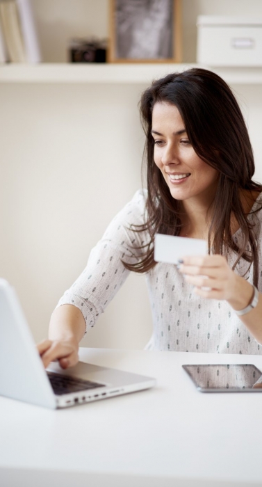Businesswoman using laptop computer for paying bills online at home office/ self employ woman in thirties